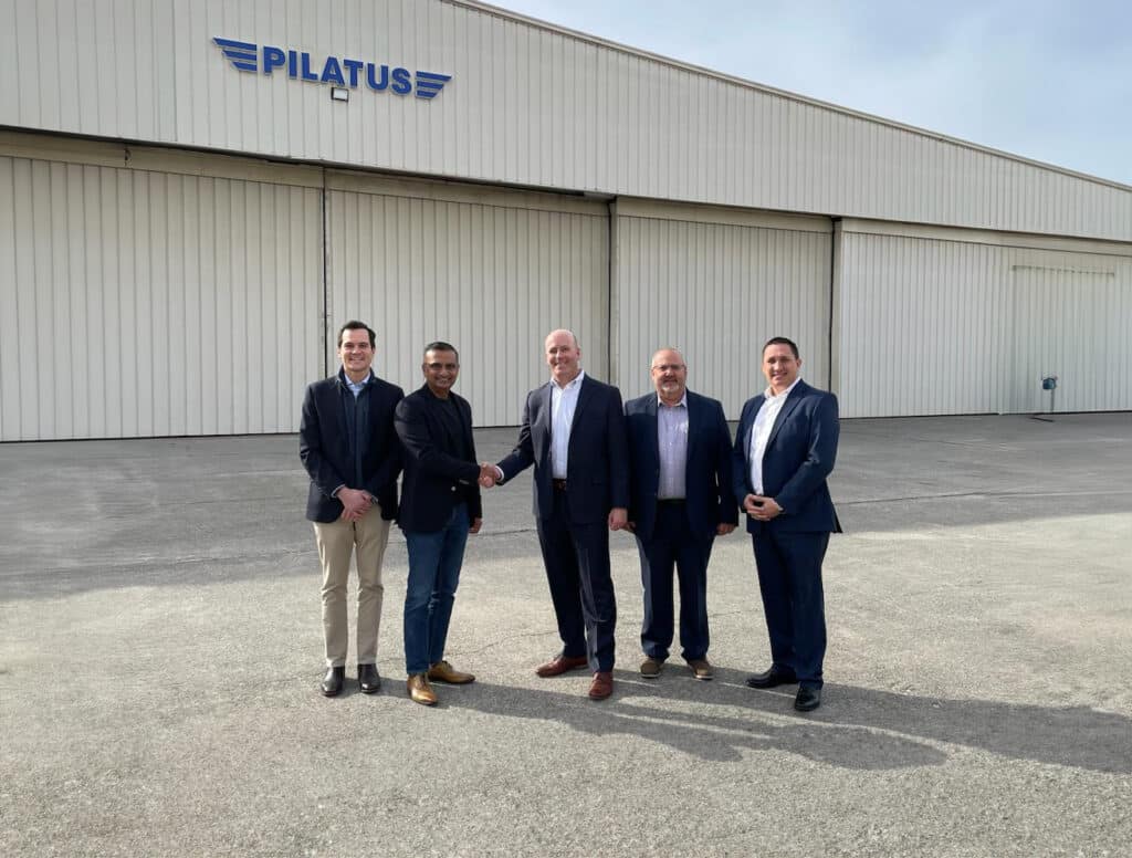 A Group of men standing in front of the Pilatus Hangar